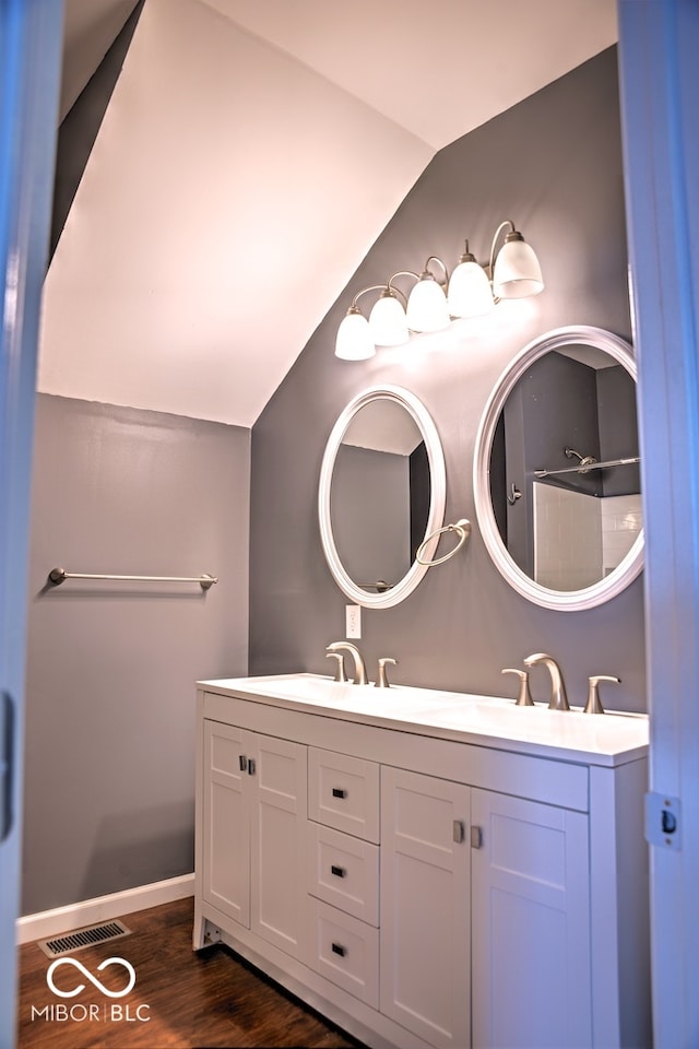 bathroom featuring vanity, vaulted ceiling, hardwood / wood-style flooring, and walk in shower