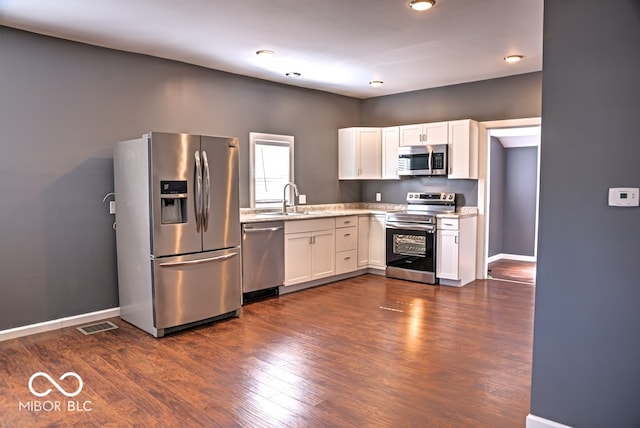 kitchen featuring dark wood-type flooring, appliances with stainless steel finishes, and white cabinetry