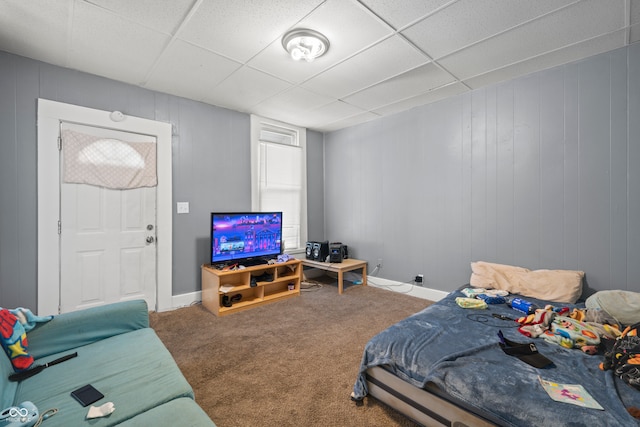 carpeted bedroom featuring a drop ceiling and wood walls