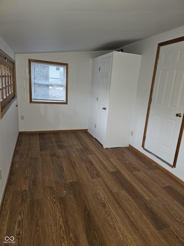 empty room featuring dark wood-type flooring and vaulted ceiling