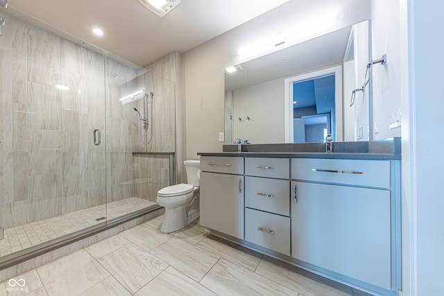 bathroom with vanity, toilet, and a shower with door