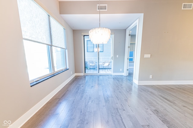 unfurnished dining area with light hardwood / wood-style flooring and a chandelier