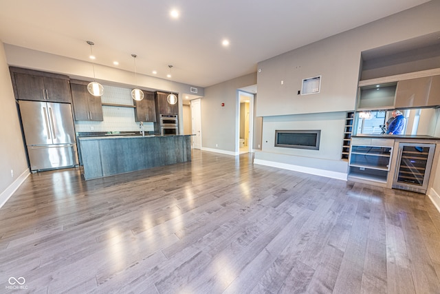 unfurnished living room with wine cooler, sink, and wood-type flooring