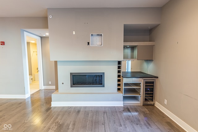 unfurnished living room with wine cooler and hardwood / wood-style flooring