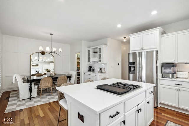 kitchen with white cabinets, hanging light fixtures, a center island, and hardwood / wood-style floors