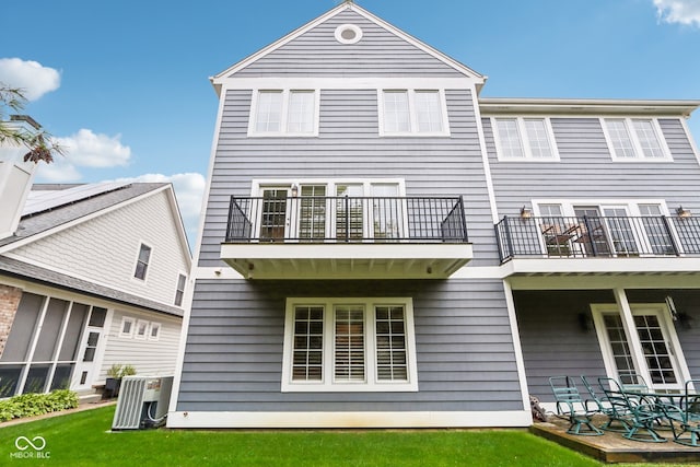 rear view of house featuring a balcony, a patio, cooling unit, and a lawn