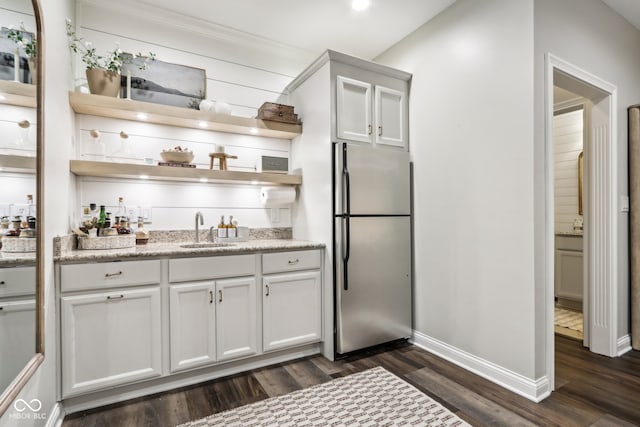 kitchen featuring dark wood-type flooring, sink, stainless steel fridge, white cabinets, and light stone counters