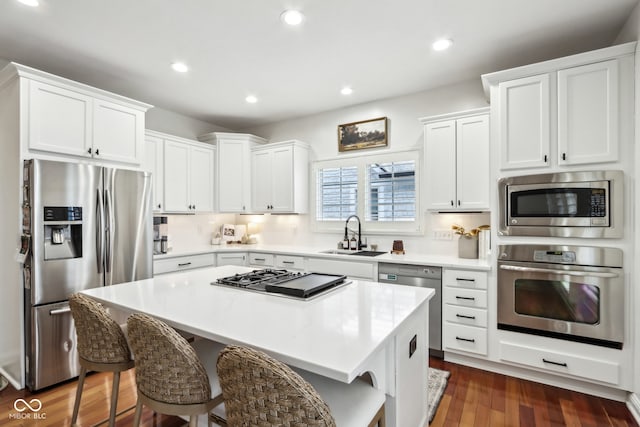 kitchen featuring white cabinetry, stainless steel appliances, sink, and a kitchen island