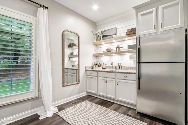 kitchen featuring white cabinetry, dark hardwood / wood-style floors, light stone counters, and stainless steel refrigerator