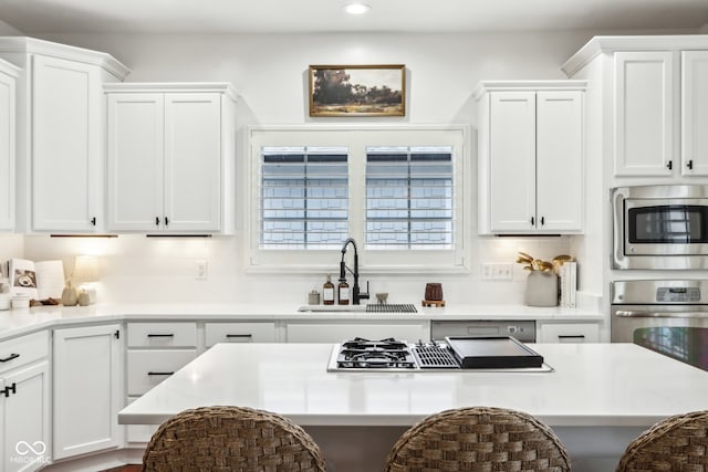 kitchen with sink, appliances with stainless steel finishes, white cabinetry, and tasteful backsplash