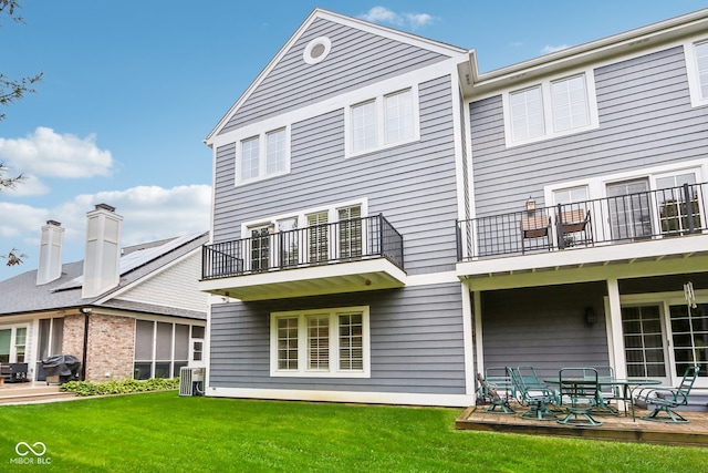 back of house with central air condition unit, a yard, and a balcony