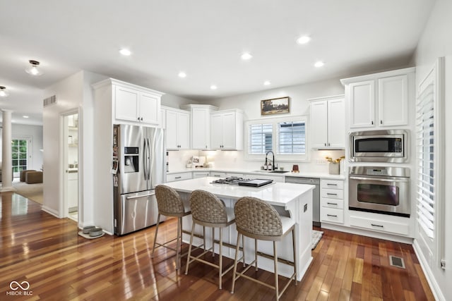 kitchen with sink, a center island, dark hardwood / wood-style flooring, white cabinetry, and stainless steel appliances