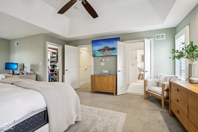 bedroom with a walk in closet, light colored carpet, a closet, and ceiling fan