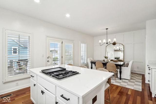 kitchen with a wealth of natural light, stainless steel gas stovetop, decorative light fixtures, and a kitchen island