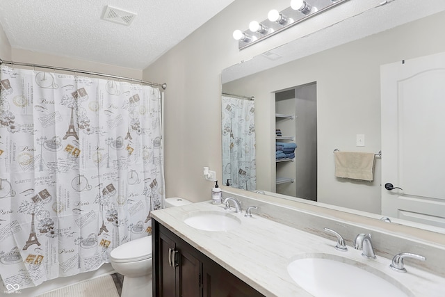 bathroom with toilet, a textured ceiling, walk in shower, and vanity