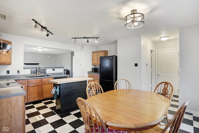 dining room featuring sink, a textured ceiling, and rail lighting