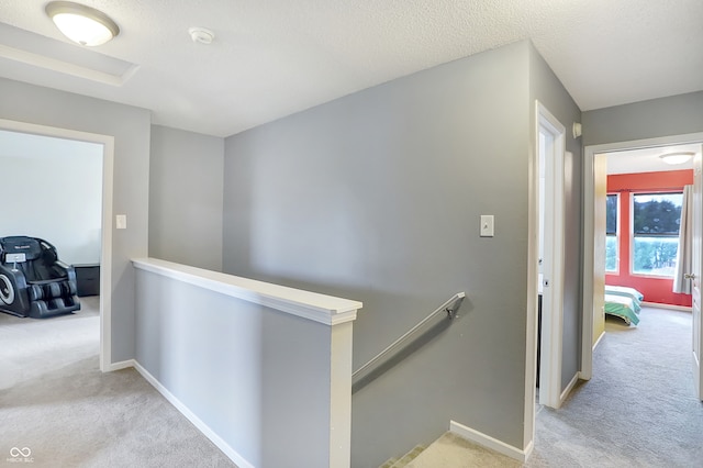 corridor with light carpet and a textured ceiling