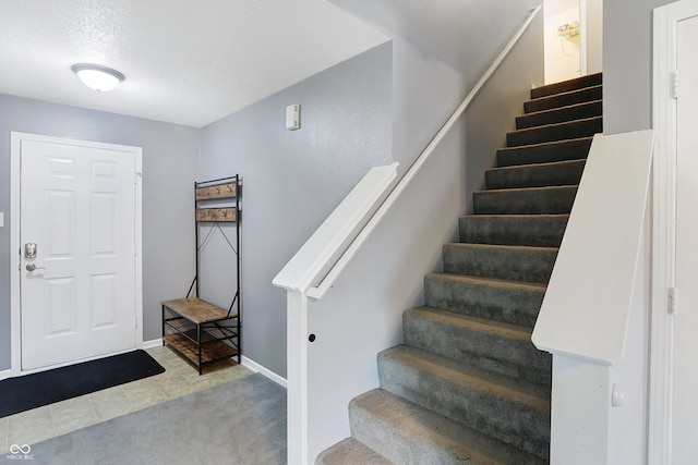 entryway with a textured ceiling and light colored carpet