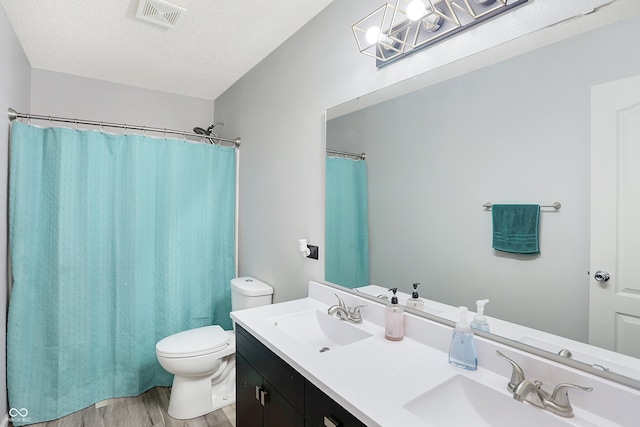 bathroom featuring hardwood / wood-style flooring, toilet, curtained shower, vanity, and a textured ceiling