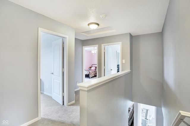 hallway featuring light carpet and a textured ceiling