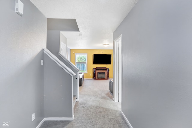 hallway featuring a textured ceiling and light colored carpet