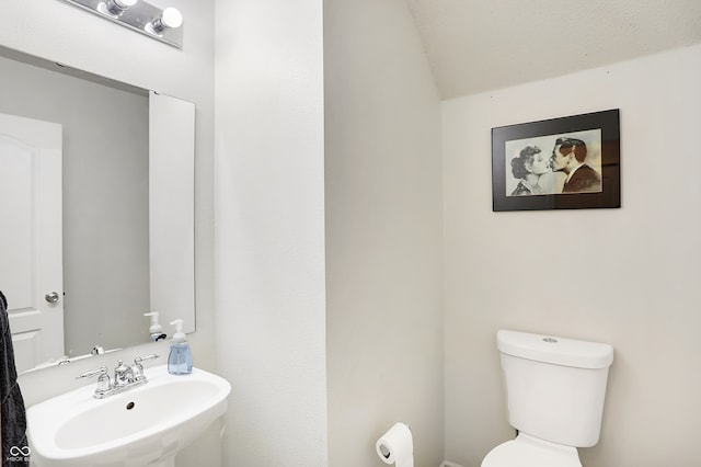 bathroom with toilet, lofted ceiling, and sink