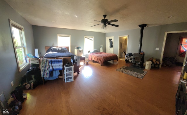 bedroom with ceiling fan, a textured ceiling, multiple windows, and hardwood / wood-style floors