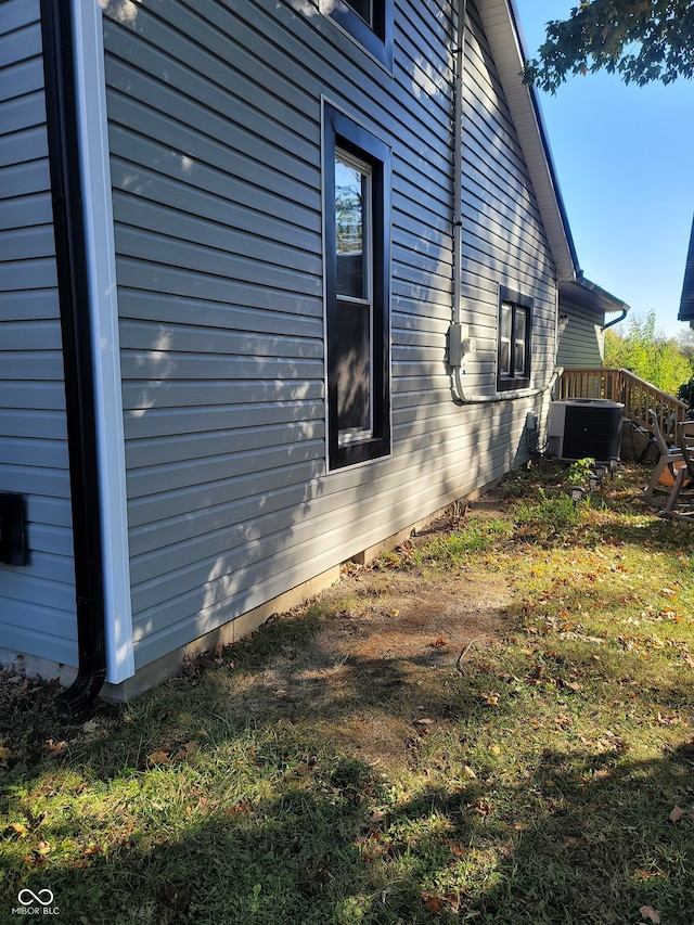 view of side of property featuring a yard and central AC unit