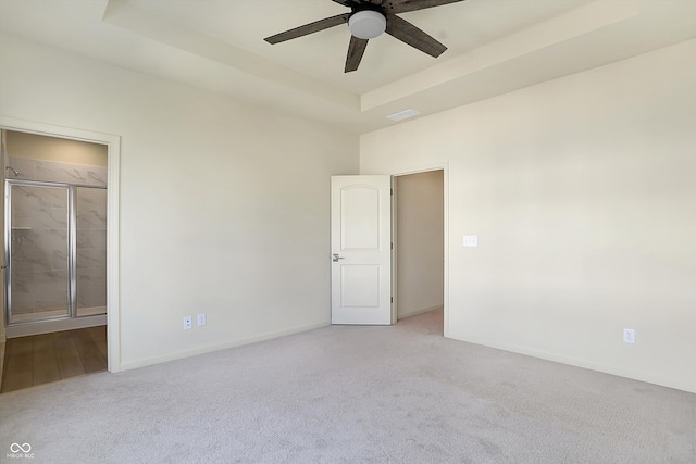 carpeted spare room with a raised ceiling and ceiling fan