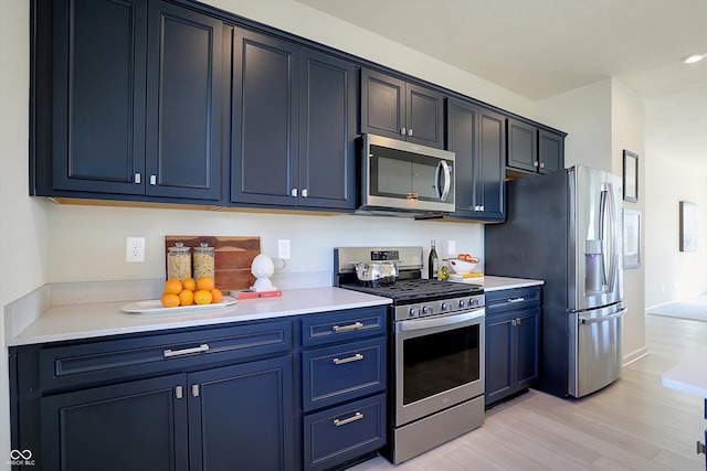 kitchen featuring blue cabinets, light hardwood / wood-style flooring, and stainless steel appliances