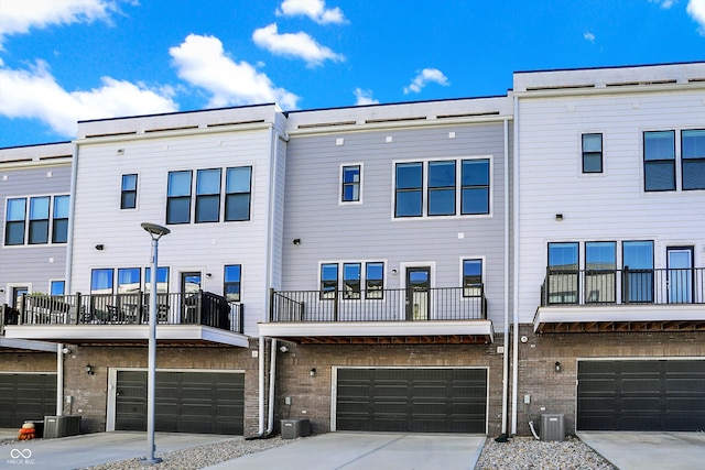 back of house featuring central AC, a balcony, and a garage