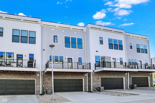 rear view of house with central AC, a balcony, and a garage