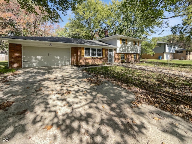 split level home featuring brick siding, an attached garage, driveway, and a chimney