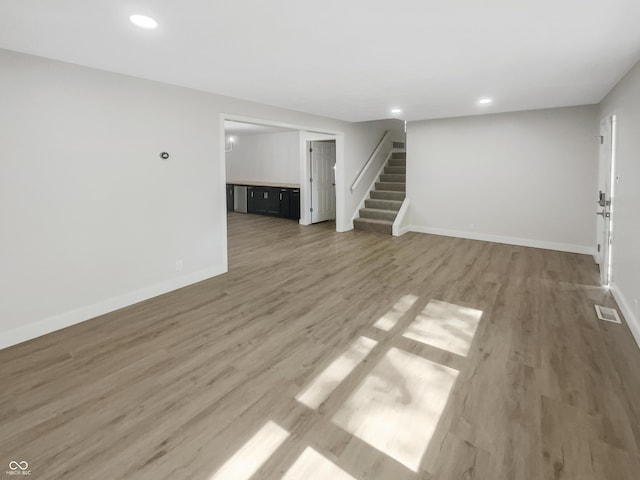 unfurnished living room featuring visible vents, stairs, baseboards, recessed lighting, and light wood-type flooring