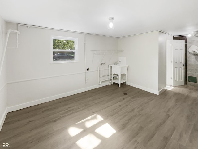 below grade area featuring a sink, baseboards, wood finished floors, and visible vents