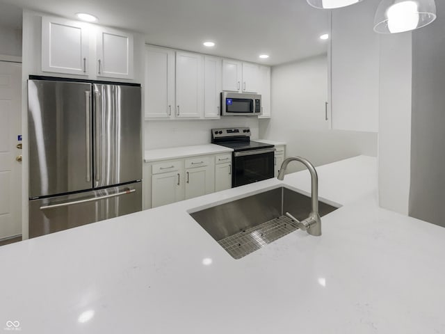 kitchen featuring recessed lighting, light countertops, white cabinets, a sink, and stainless steel appliances
