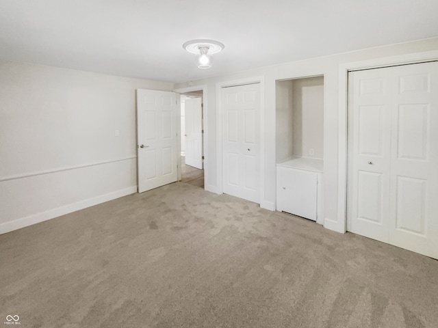 unfurnished bedroom with multiple closets and carpet flooring