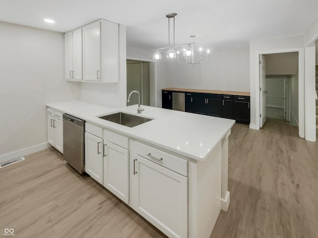 kitchen featuring sink, decorative light fixtures, stainless steel dishwasher, white cabinets, and light hardwood / wood-style floors