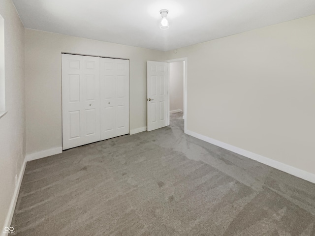 unfurnished bedroom with baseboards, carpet, and a closet