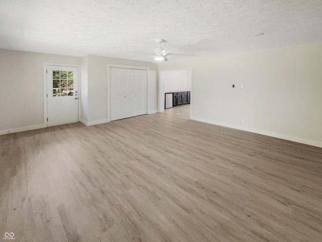 unfurnished living room featuring ceiling fan, a textured ceiling, and light wood-type flooring