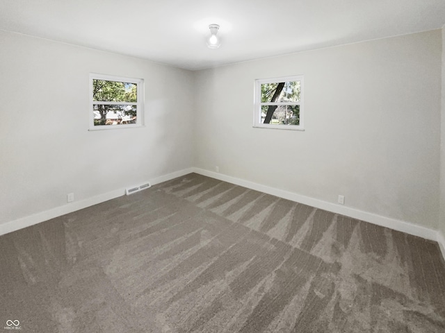carpeted empty room featuring baseboards, visible vents, and a healthy amount of sunlight