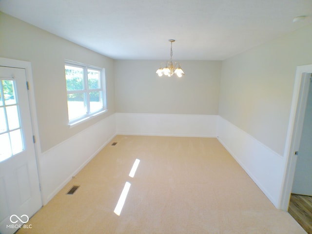 unfurnished dining area with an inviting chandelier and carpet