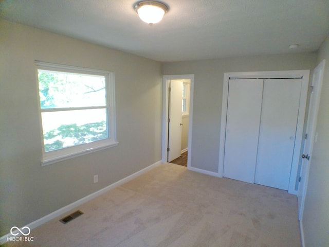 unfurnished bedroom with a closet and light carpet