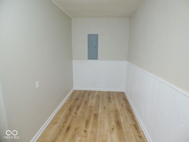 empty room with light hardwood / wood-style flooring, a textured ceiling, and electric panel