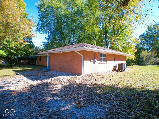 view of side of home with central AC and a lawn