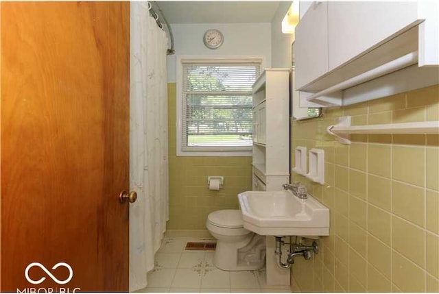 bathroom with tile walls, toilet, sink, tile patterned floors, and a shower with shower curtain