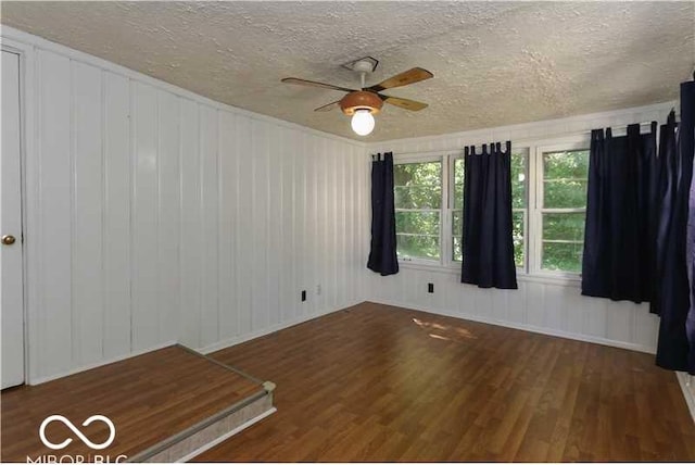 empty room featuring ceiling fan, a textured ceiling, and dark hardwood / wood-style floors