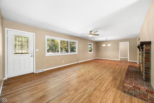 3233 Plum Creek Rd, Nashville, IN 47448 - unfurnished living room with ceiling fan, visible vents, a brick fireplace, light wood-type flooring, and baseboards