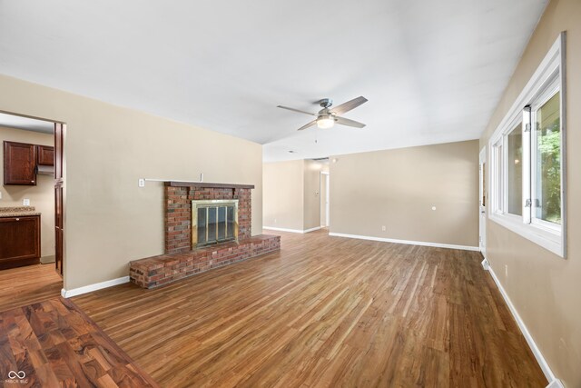 3233 Plum Creek Rd, Nashville, IN 47448 - unfurnished living room with baseboards, a ceiling fan, wood finished floors, and a brick fireplace