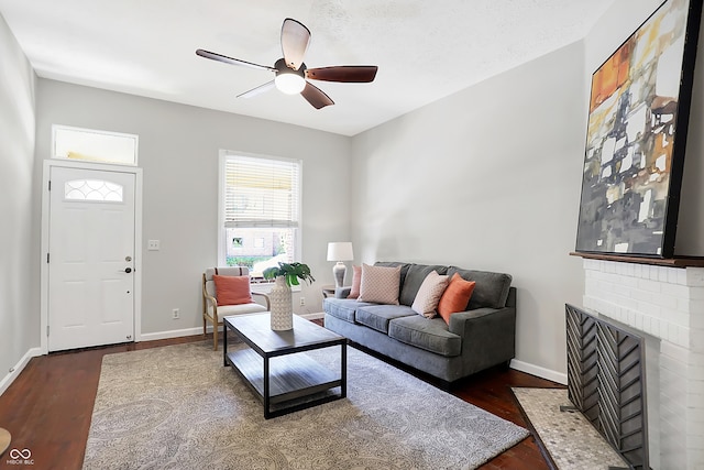 living room with dark hardwood / wood-style floors, ceiling fan, a textured ceiling, and a brick fireplace